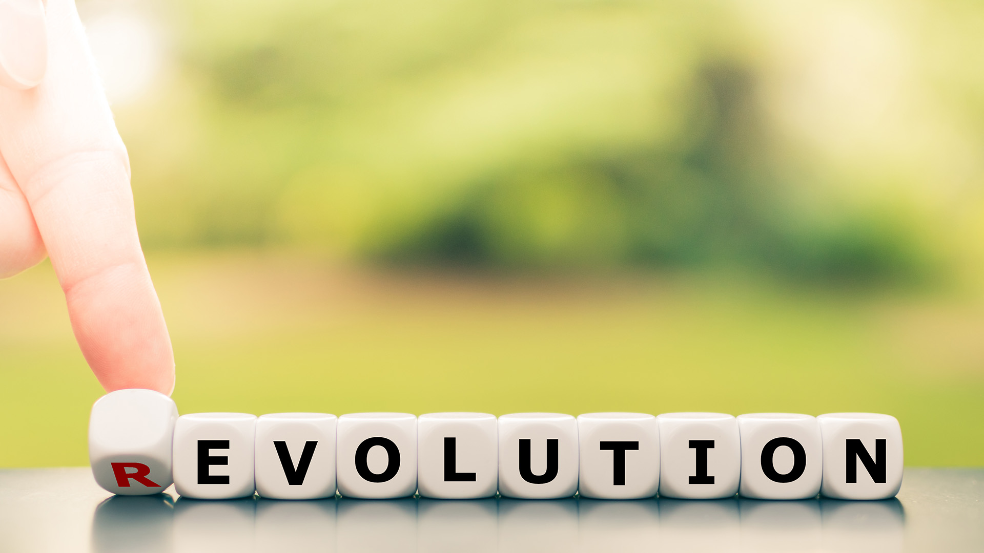 Evolution instead of revolution. Hand turns a dice and changes the word "revolution" to "evolution".